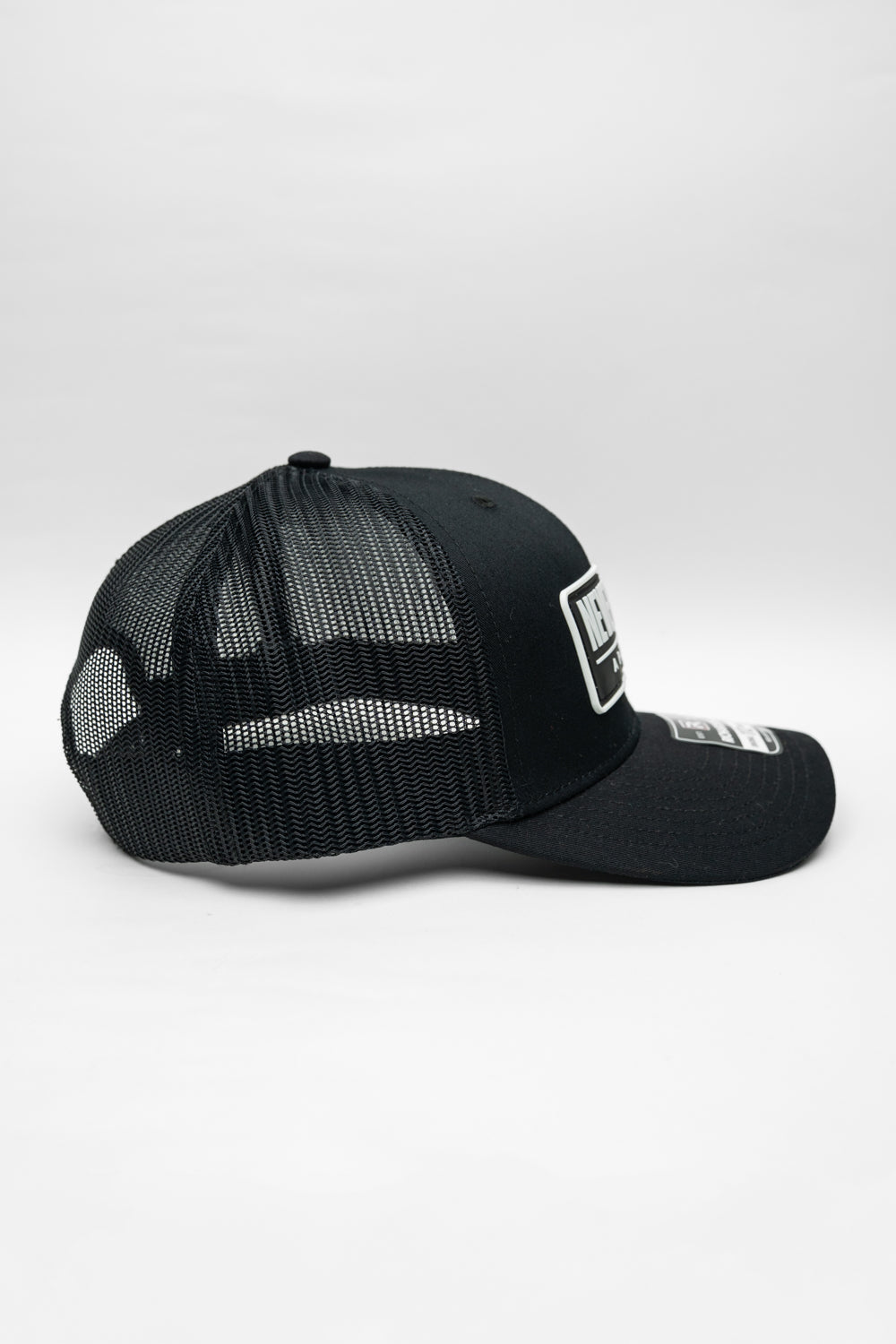 Black cap with 'Never Woke Apparel' logo on a black background with white boarder and letters