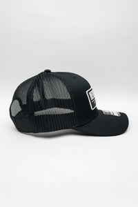 Black cap with 'Never Woke Apparel' logo on a black background with white boarder and letters